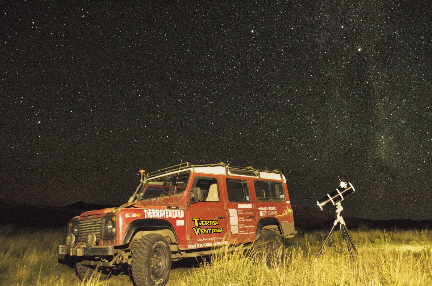 Defender 4x4 y telescopio bajo el cielo estrellado